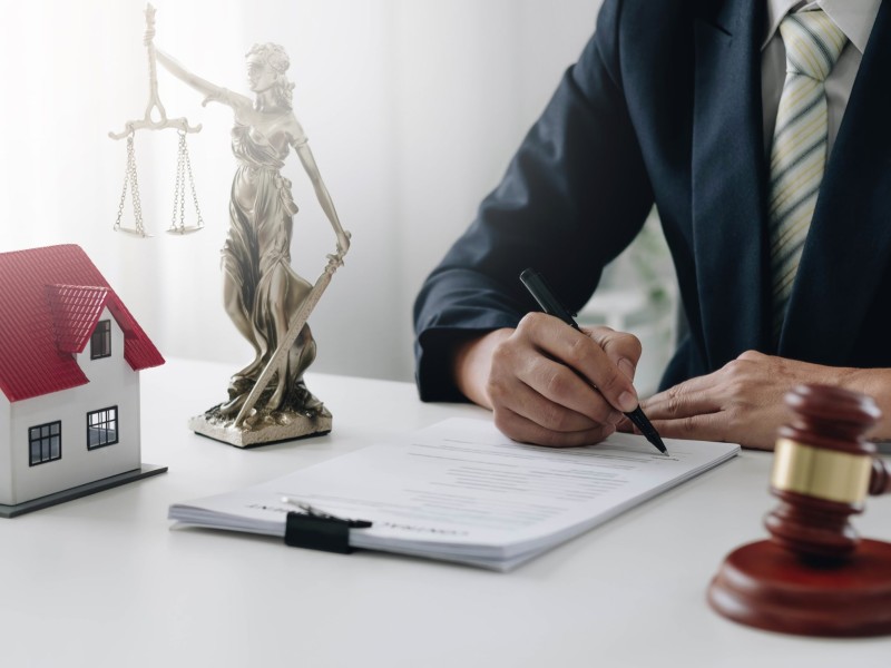 Judge gavel and house model on the table. Man signing in document. Real Estate Lawyer.